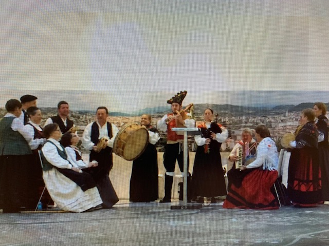 Imaxe do grupo Charamuscas fotografiado ao borde do mar mentras interpretan unha das súas pezas ataviados con traxes tradicionais galegos