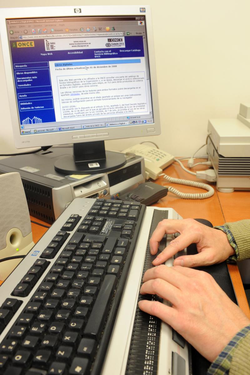 En la imagen se ven unas manos sobre un teclado de ordenador y en la pantalla el acceso a laBiblioteca Digital ONCE