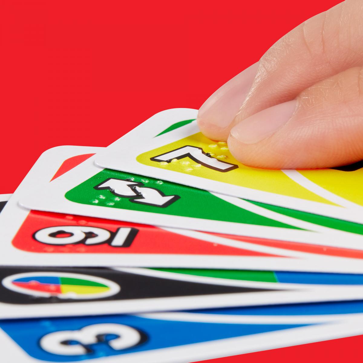 En la imagen se ve una mano que sostiene un grupo de cartas del juego UNO 