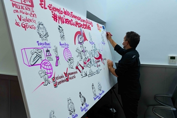 Una persona hace su paportación gráfica a un enorme panel  para sumarse a apoyar la lucha contra la Violencia de Género