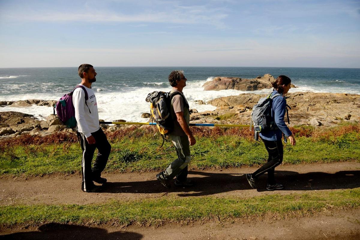 En la imagen Julia, Roberto y Dani, sujetos a la barra de dirección caminan al borde del Atlántico en ruta por el Camino Portugués a Santiago