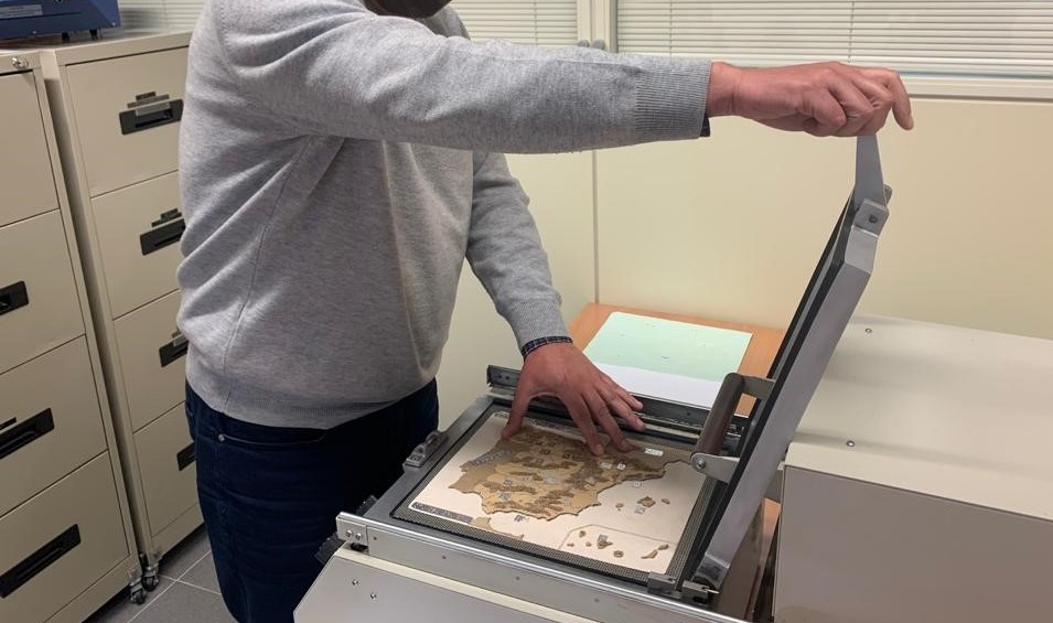 En la imagen se ve a un técnico de ONCE manejando una impresora para reproducir un mapa de la Península Ibérica en relieve