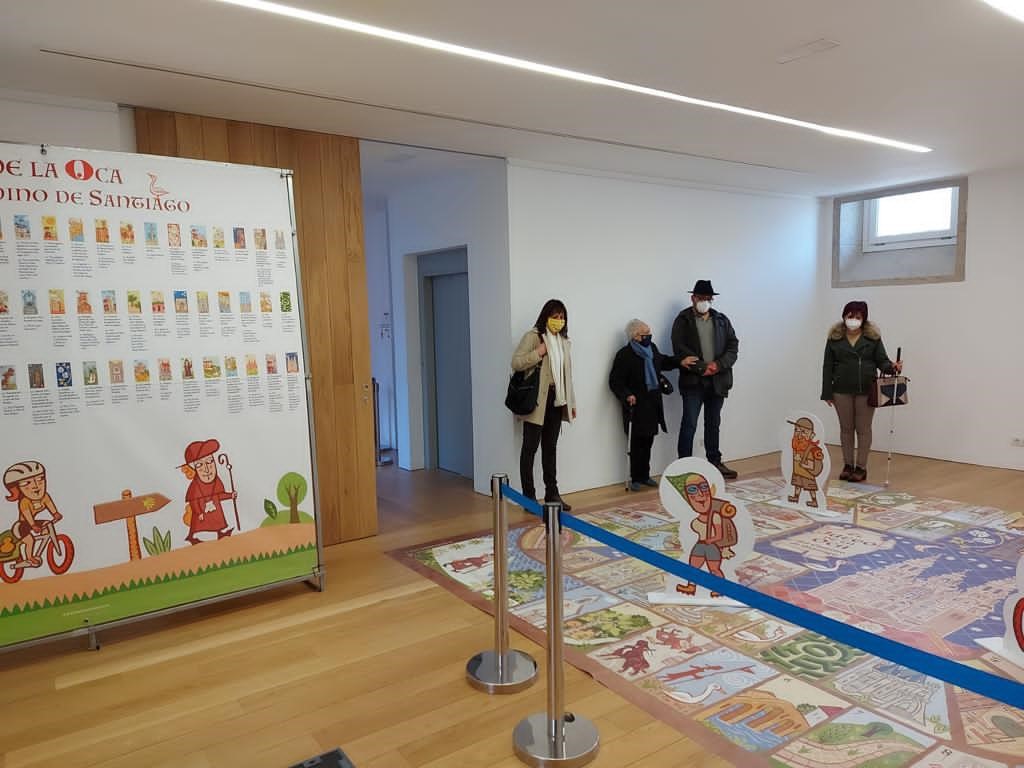 En la fotografía loos afiliados que visitaron la exposición posan ante el enorme panel que reproduce el juego de la Oca pero alusivo al Camino Francés de Santiago