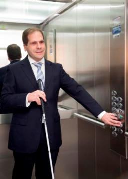 Imagen de un hombre ciego presionando la botonera de un ascensor. Una imagen que se va a acabar