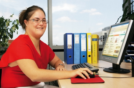 Una joven con síndrome de down desarrollando su trabajo administrativo en una oficina