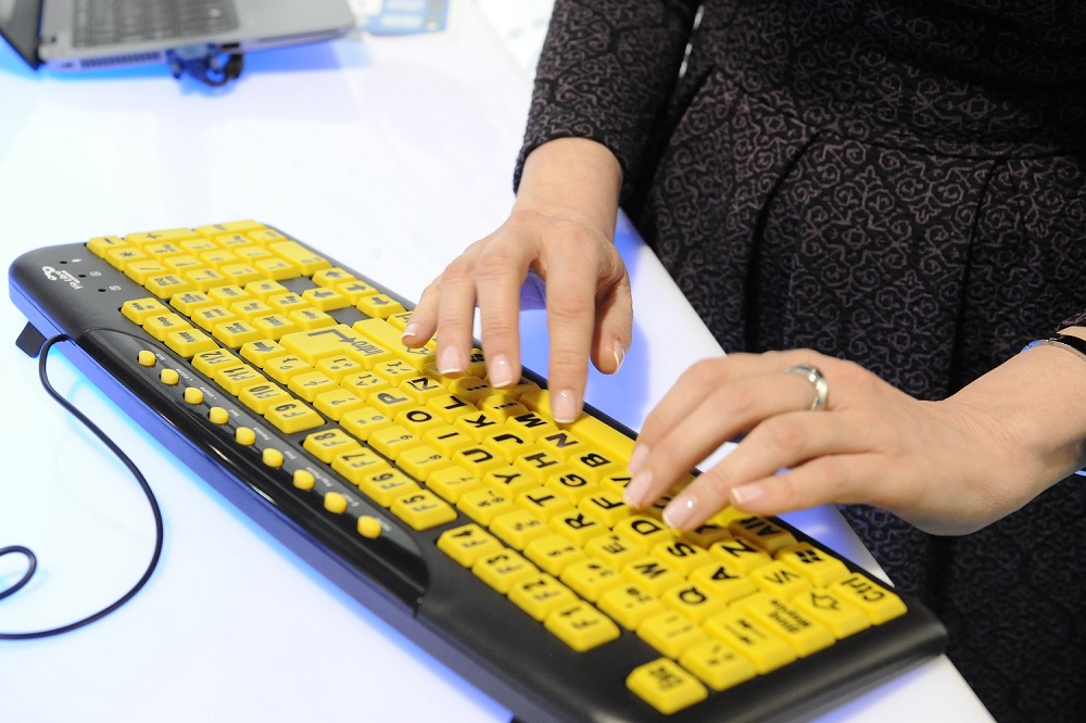 En la fotografía se ven las manos de una mujer manejando un teclado adaptado 
