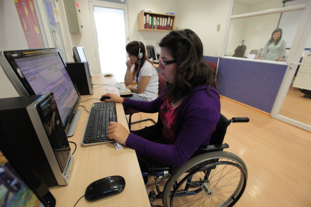 Dos  mujeres jóvenes con discapacidad ante sus ordenadores  en la jornada laboral