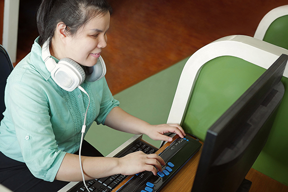Una joven con discapacidad en su puesto de trabajo ante un ordenador