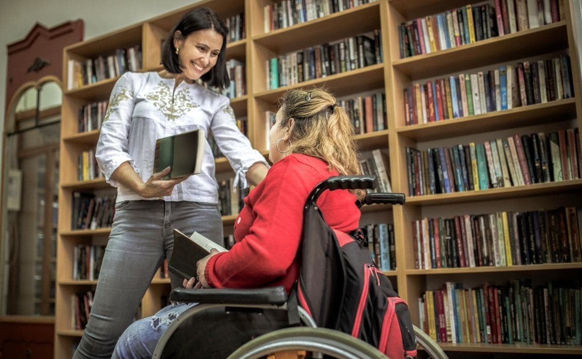 Una estudiante con discapacidad, en silla de ruedas, en una biblioteca de un centro educativo