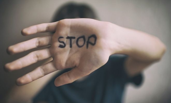 La palma de  una mano de una joven lleva escrita la palabra STOP