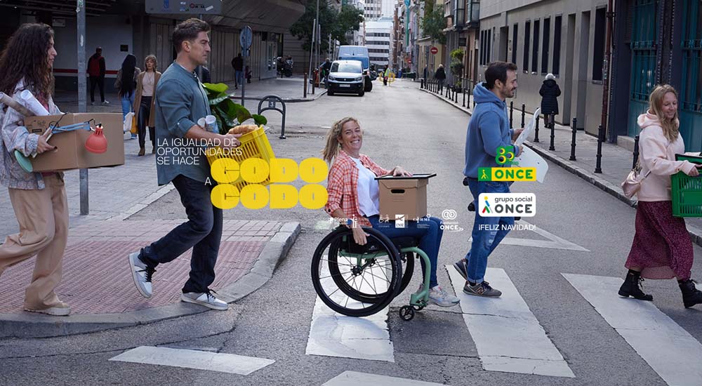 Cinco personas, una de ellas en silla de rueda, cruzan por un paso de cebra con cajas de mudanza