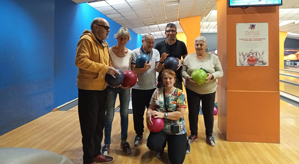 Afiliados en la bolera sosteniendo una bola 