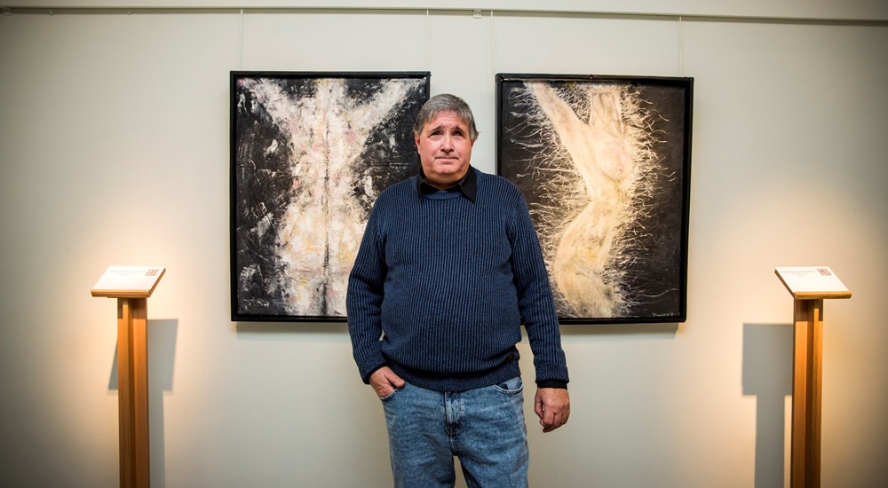 XavierE, entre dos de los cuadros que expone en el Museo Tiflológico de la ONCE