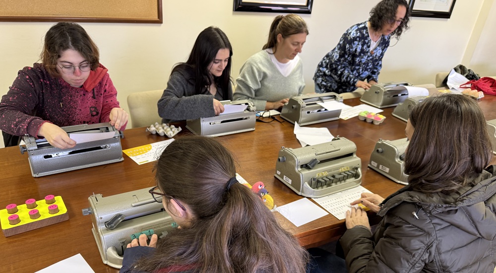 Un grupo de personas en un taller de braille utilizando la máquina perkins