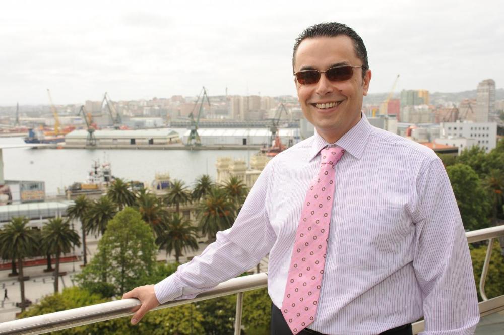 Manuel  Martínez asomado a la terraza del edificio de la Delegación Territorial con el puerto de A Coruña al fondo
