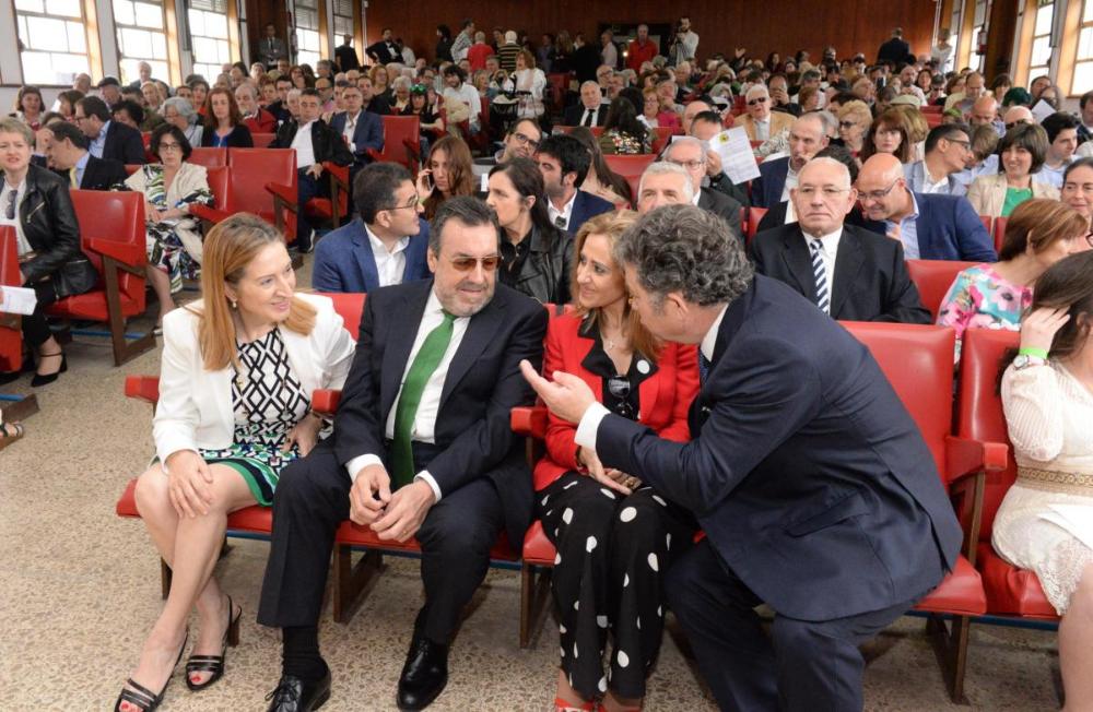 Vista general del salón de actos, lleno de gente,  tomada desde el escenario hacia la puerta