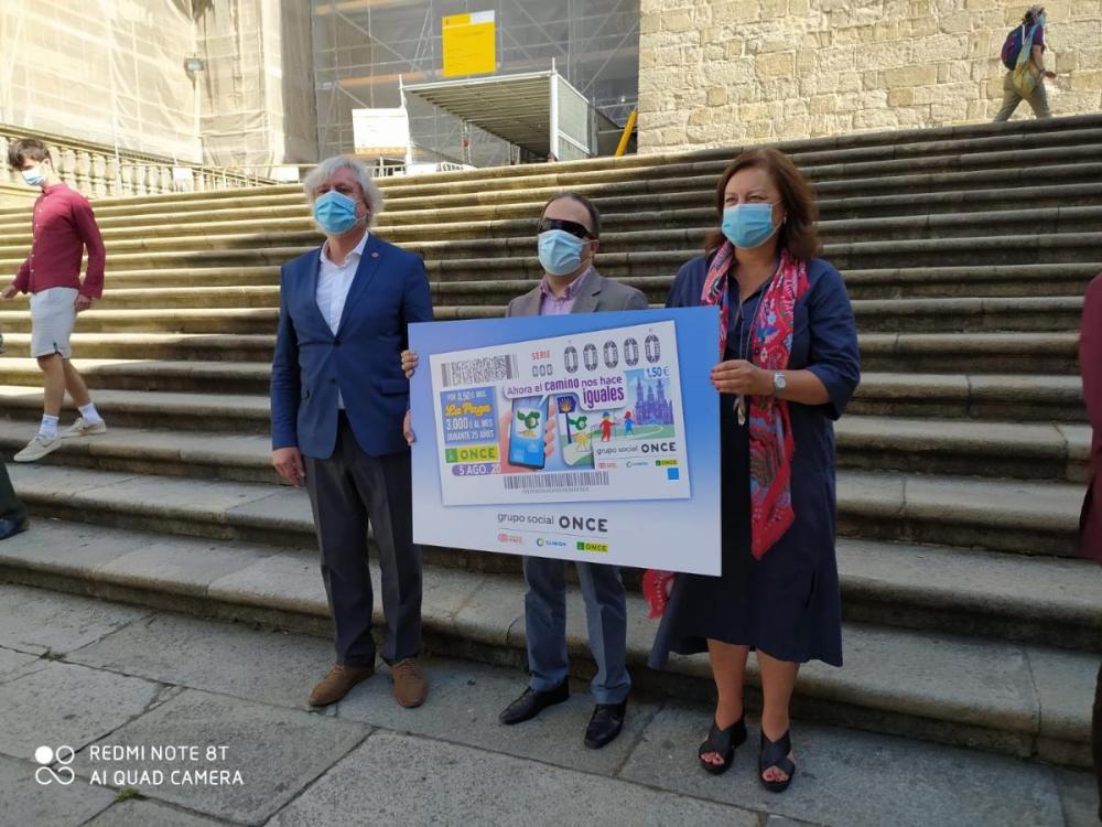 En la imagen aparecen el presidente del Consejo Territorial y la comisaria del Xacobeao 2021 sosteniendo la reproducción del cupón del 5 de agosto, y a la izquierda se ve al secretario xeral de la Consellería de Cultura