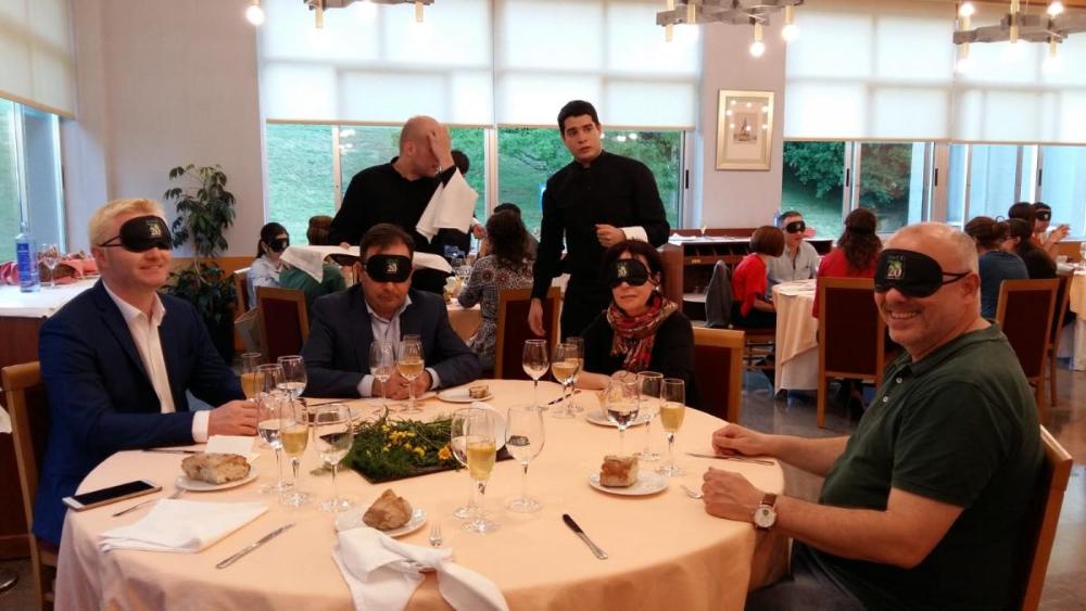 Imaxe ddunha das mesas con tódolos comensais  privistos de antifaz