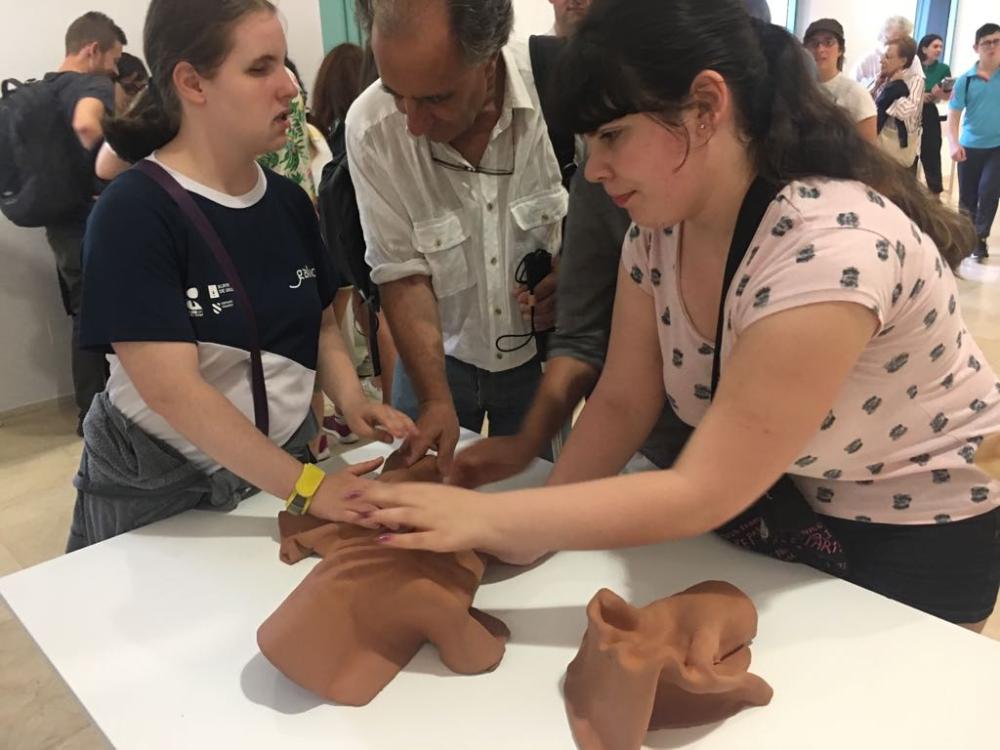 Dos chicas tocan una de las obras de la muestra Proxecto Táctil
