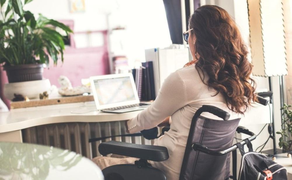 Una mujer joven con discapacidad física en su puesto de trabajo en una oficina