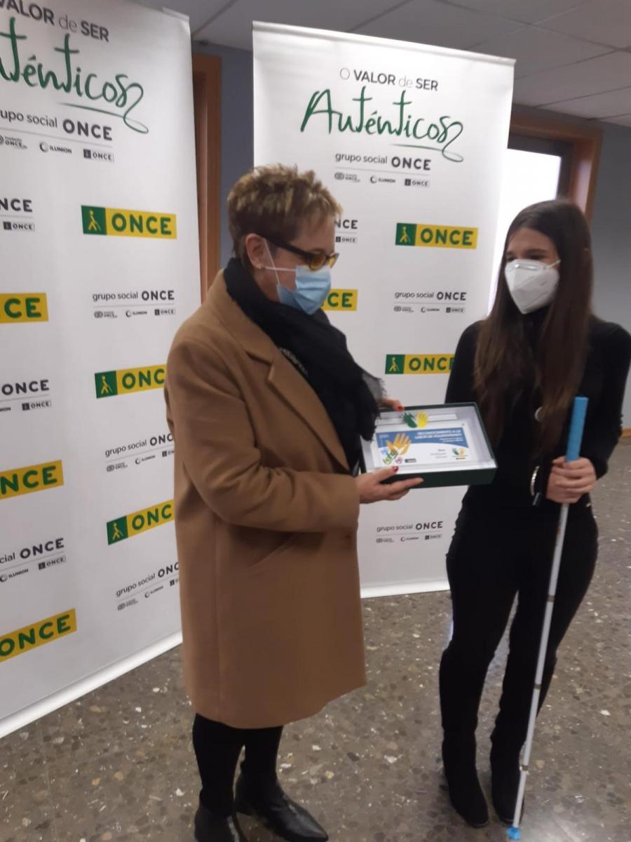 Fotografía de la voluntaria Elisa Rodríguez recibiendo el reconocimiento por su labor de manos de la subdirectora de ONCE en Vigo, Lorena Fernández