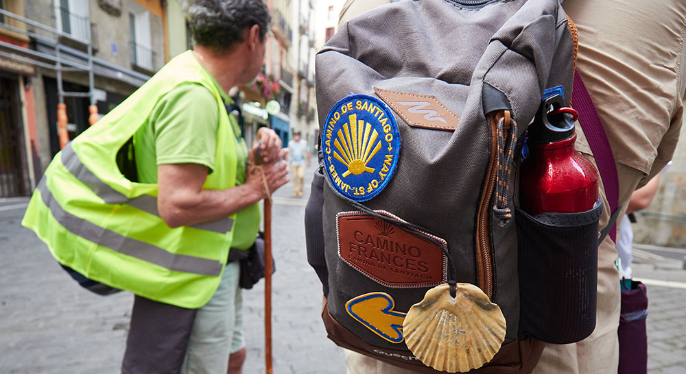 Foto de la mochila de un peregrino con símbolos del Camino de Santiago