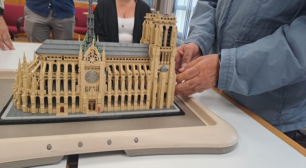 Las manos de una persona ciega tocando la maqueta de Notre Dame